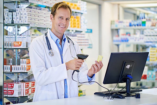 A pharmacist scanning the price on a bottle of pills. The commercial product(s) or designs displayed in this image represent simulations of a real product, and are changed or altered enough so that they are free of any copyright infringements. Our team of retouching and design specialists custom designed these elements for each photo shoot