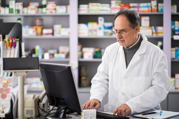 Senior pharmacist using desktop PC while working in a pharmacy.